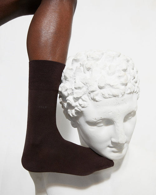 Model wearing Unisex Mid Length Cotton Socks in Dark Brown - CDLP