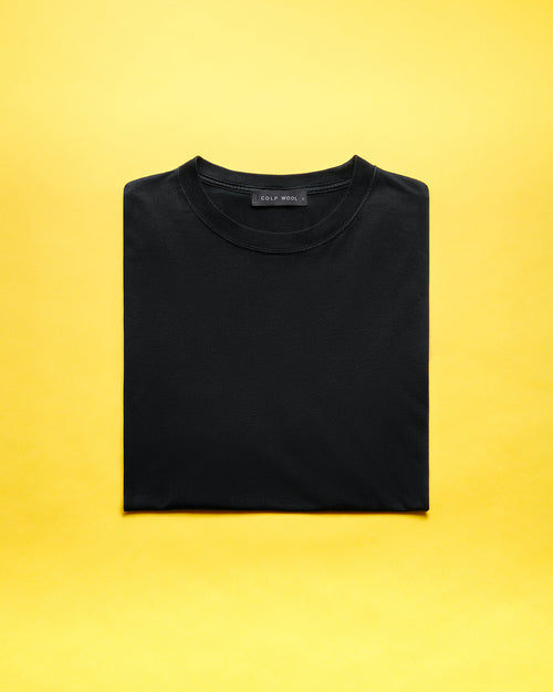 A neatly folded black t-shirt centered on a vibrant yellow background.