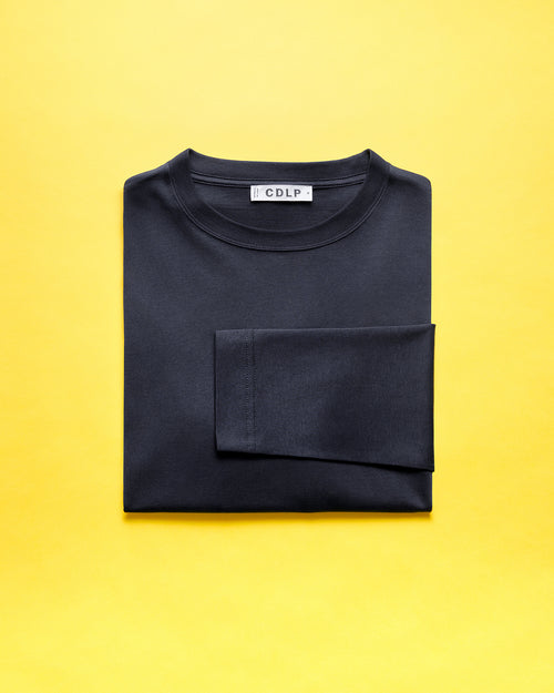 A folded dark t-shirt showing the CDLP brand label on a vibrant yellow background.