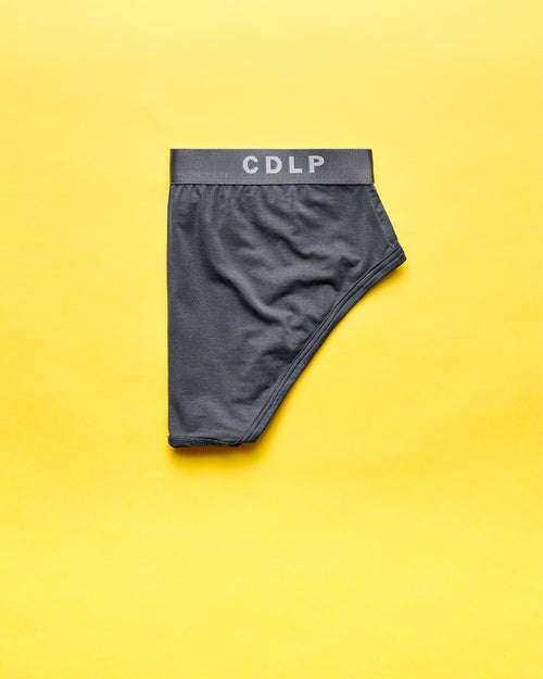 Dark grey brief with a branded elastic waistband on a yellow background.