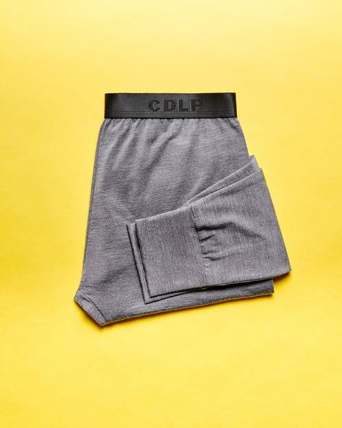 Folded grey underwear with a black branded waistband on a yellow background.