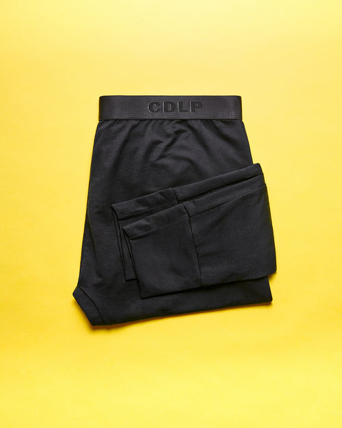 Black boxer briefs folded neatly on a vibrant yellow background, featuring the CDLP logo on the waistband.