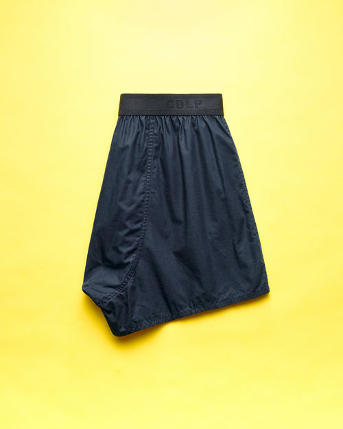 Dark blue boxer shorts with a branded waistband on a yellow background.