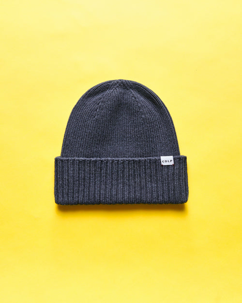 Dark grey knitted beanie with a folded cuff and a small white CDLP logo tag.
