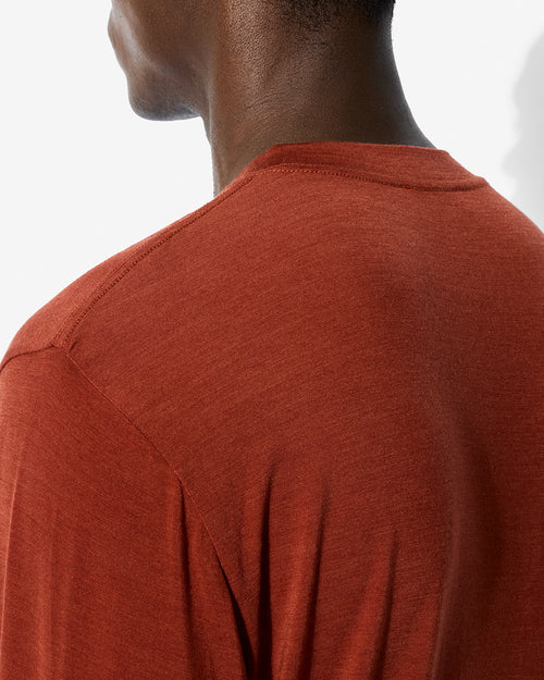 Close-up of the rust Merino Blend Long Sleeve T-Shirt highlighting the crew neck and shoulder seam construction on a model.