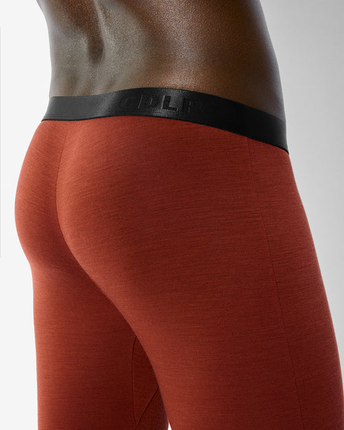 Our Merino Blend Long Johns in Rust worn with a snug fit and signature black waistband, viewed from the back.