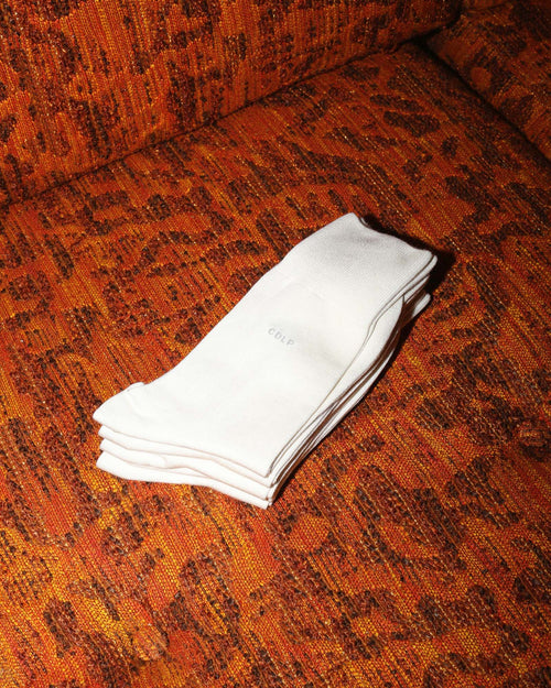 Mid-Length Socks in White folded on couch