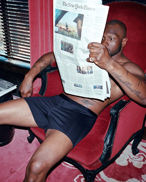 Marcus sitting in an armchair reading the newspaper wearing Lyocell Boxer Shorts in Navy Blue