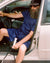 Sébastien sitting in the car wearing Home Shirt Short-Sleeve in Navy Blue